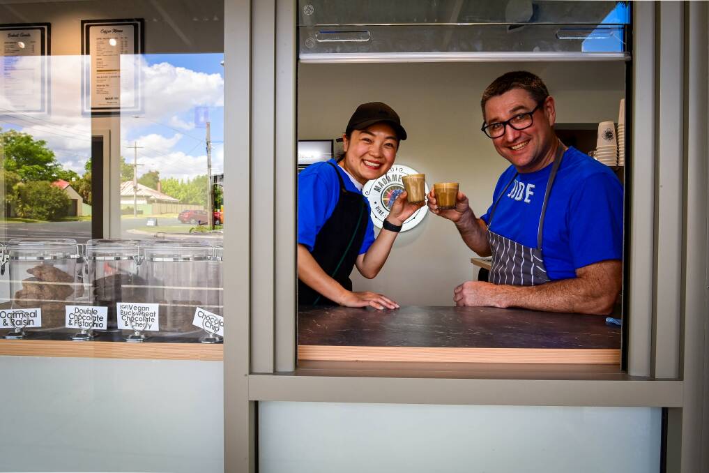 Yaya Hou and Owen Stuchberry raise a glass through the cafe's coffee hatch. Picture by Brendan McCarthy