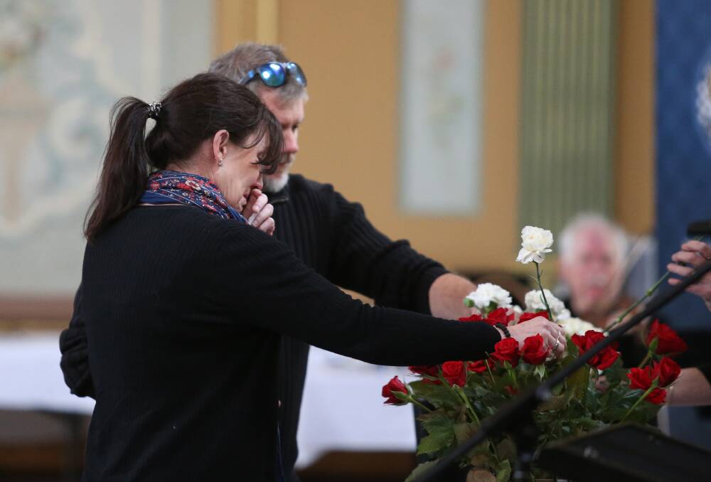 Attendees place white flowers among the 21 roses symbolising each of the 21 members who had died in the past 12 months. Picture: GLENN DANIELS