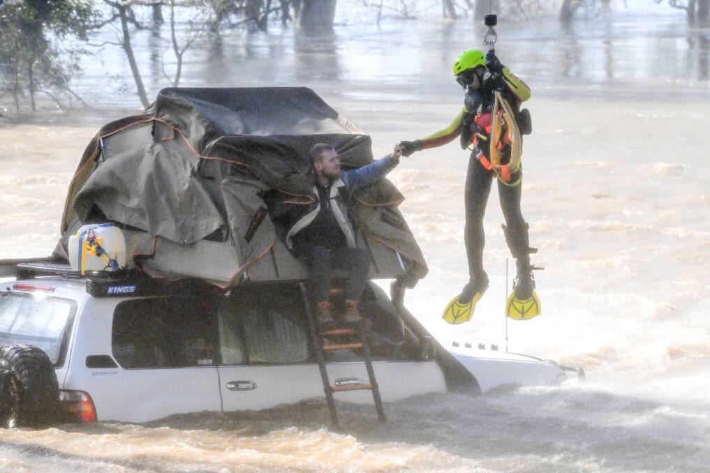 The HEMS helicopter crew member rescues two campers from flood waters at the Newbridge campground on Saturday. Picture by Darren Howe.