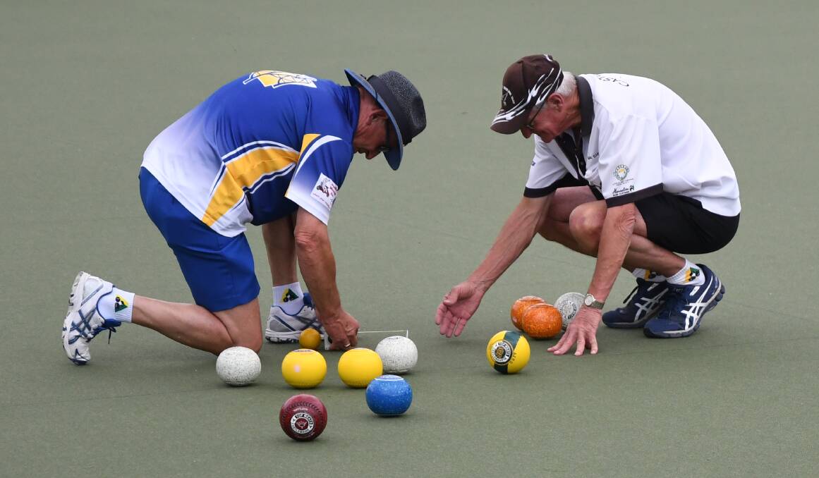CLOSE CALL: Golden Square's Wayne Robins and Castlemaine's Mal Darroch get the tape measure out during their game on Saturday. Golden Square proved too strong for the Maine, winning 106-85. Pictures: LUKE WEST