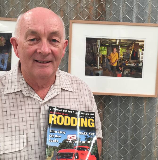 ANNIVERSARY: Larry O'Toole poses in front of a photo of him in his workshop with a copy of Australian Street Rodding. Picture: CHRIS PEDLER