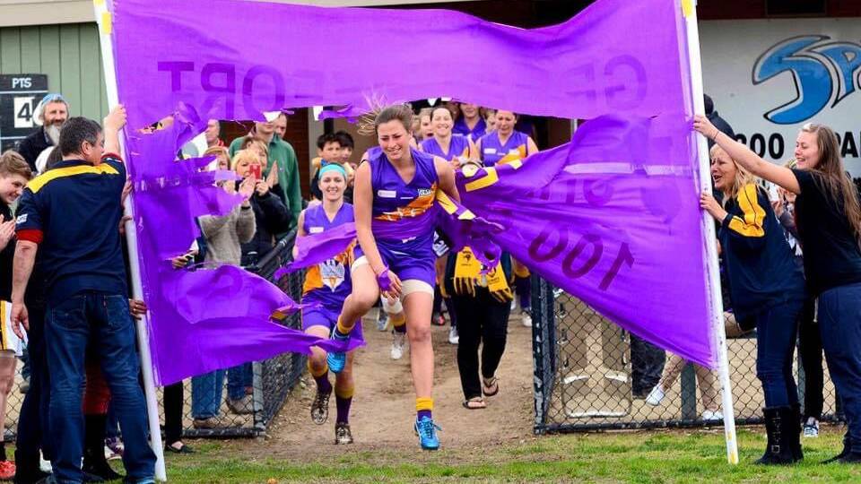 Shae Murphy breaks through the banner for her 100th game of football, which was played for Altona Vikings against her current team, Bendigo Thunder.