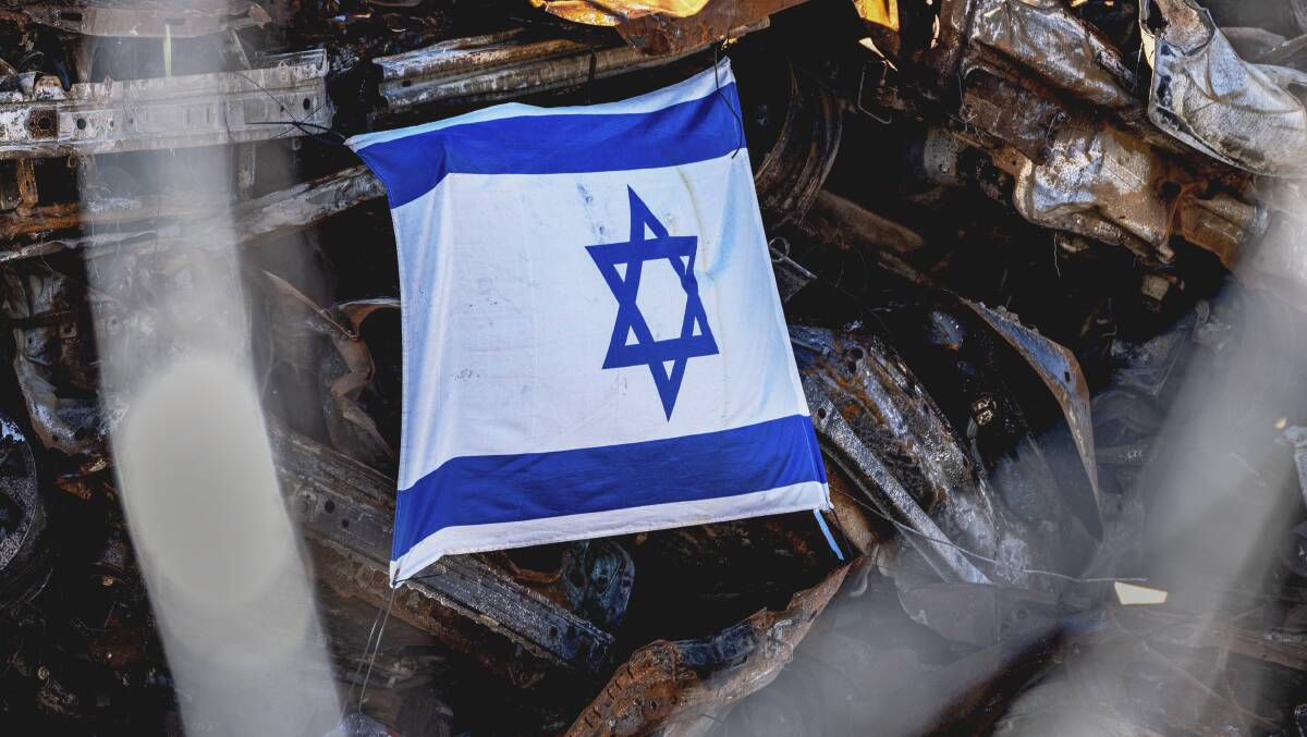 An Israeli flag on the remains of a car torched in the October 7 attacks. Picture AP